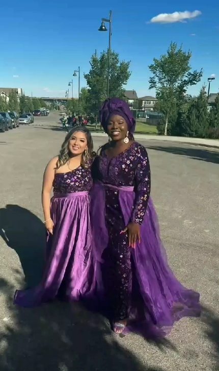 Two women in matching purple outfits sewn at Jovibest Fashions